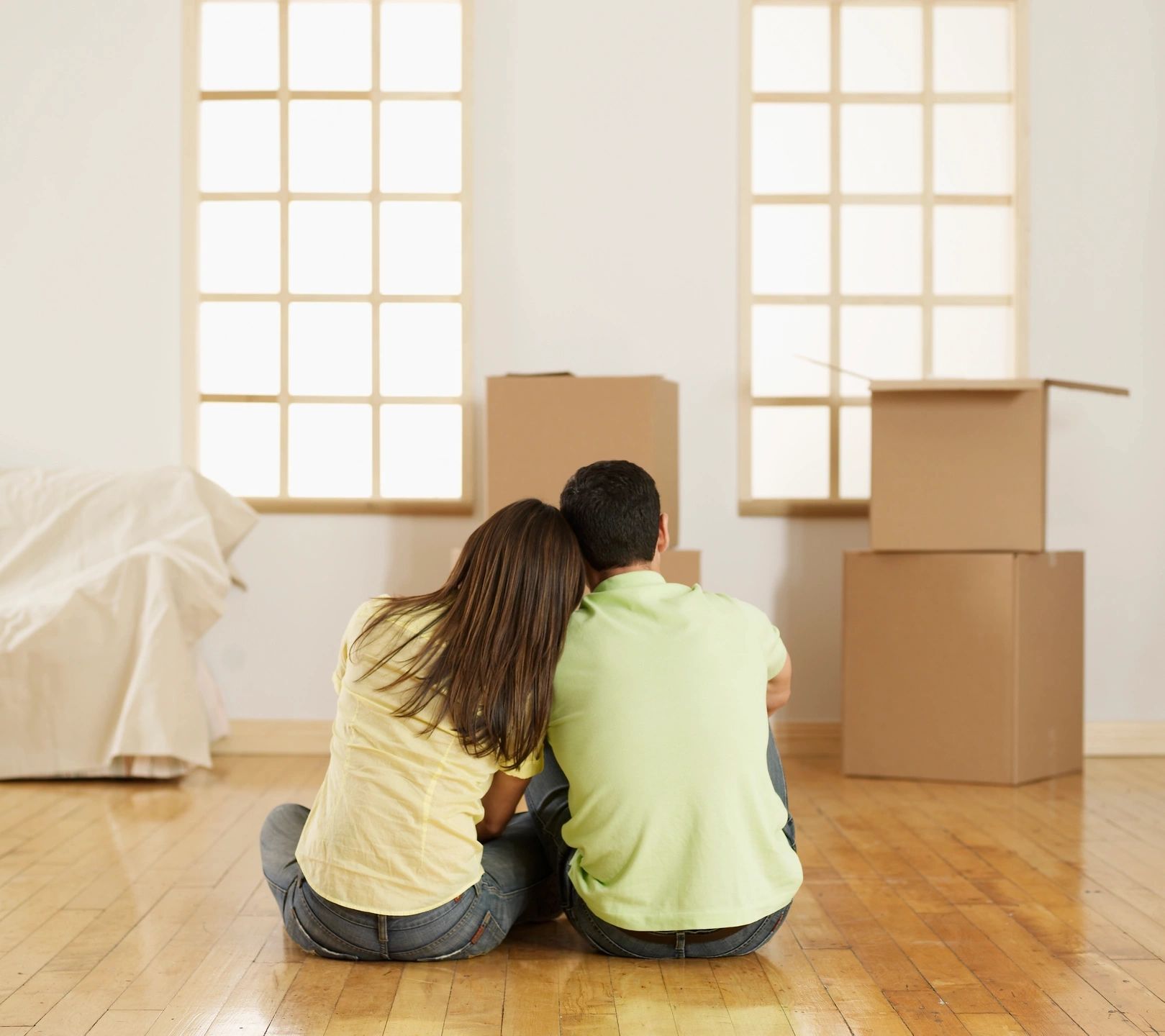 Couples sitting on the floor surrounded by moving boxes in their new home after relocating from Naples, Florida to out of state.