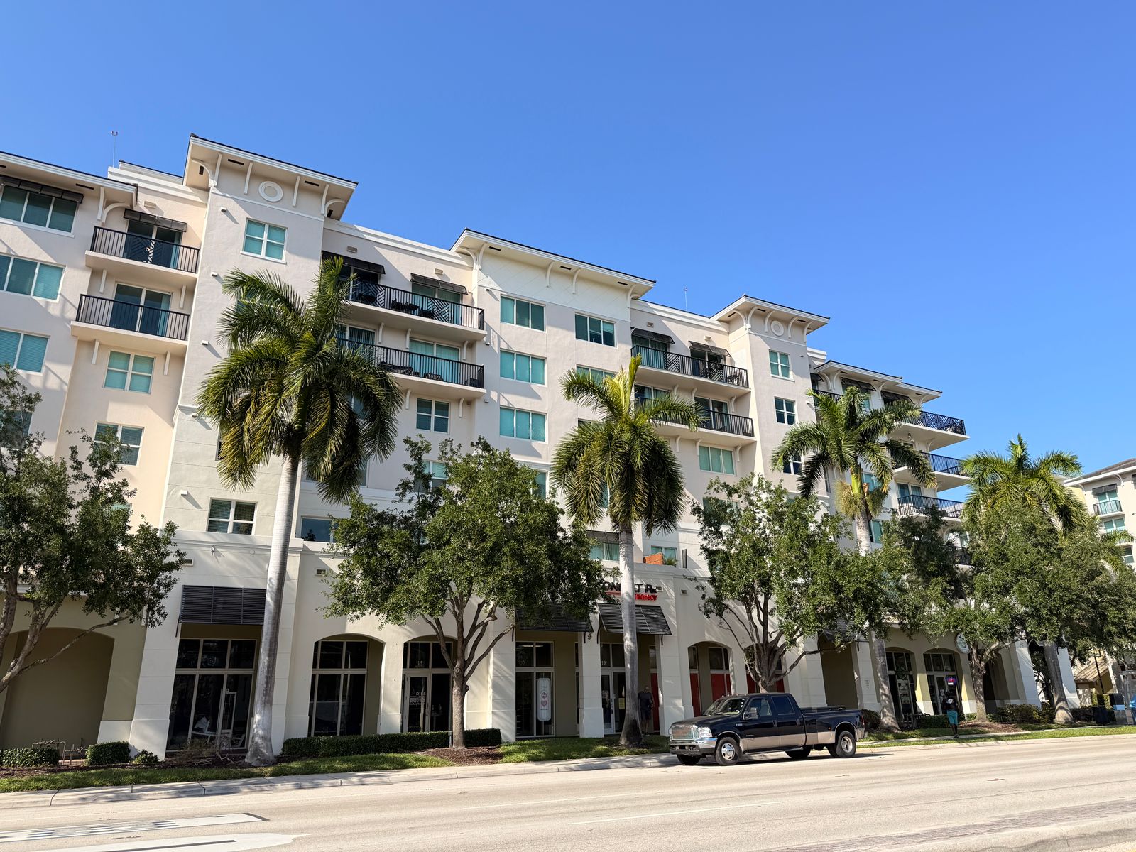 Florida mid-rise condominium building with royal palm trees, subject to milestone inspection and SIRS requirements