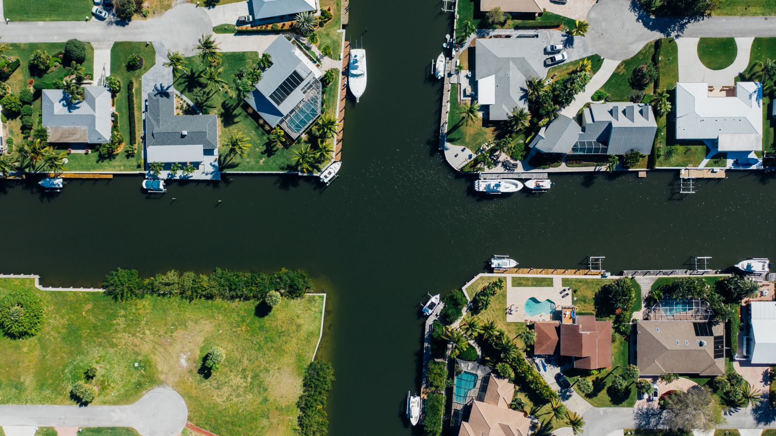 Aerial view of a Southwest Florida canal neighborhood with private boat docks, lifts and screened pools