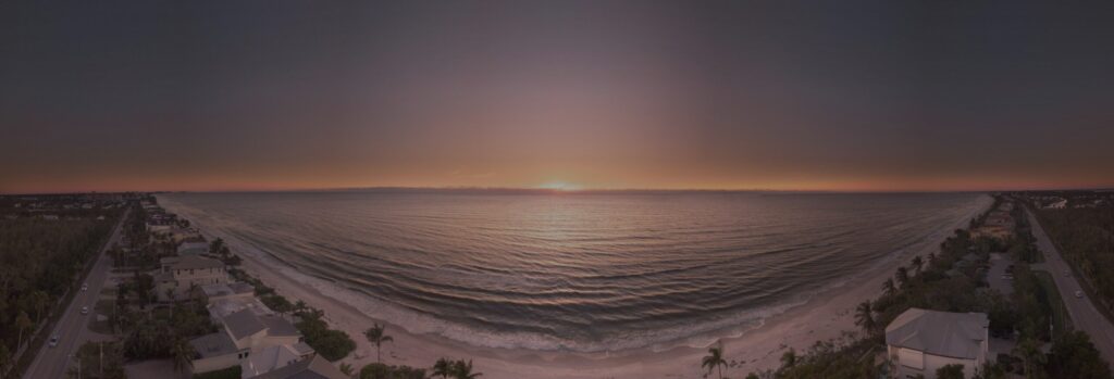 A Gulf beach in Naples, Florida at sunset, with homes along the shoreline